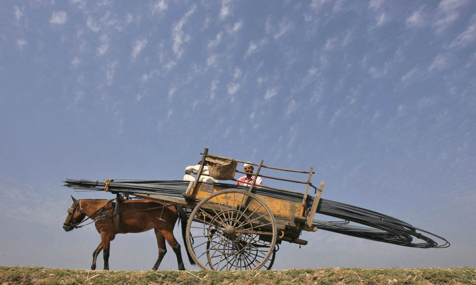 People transport iron rods on a horsecart to a construction site of a residential complex on the outskirts of Jammu