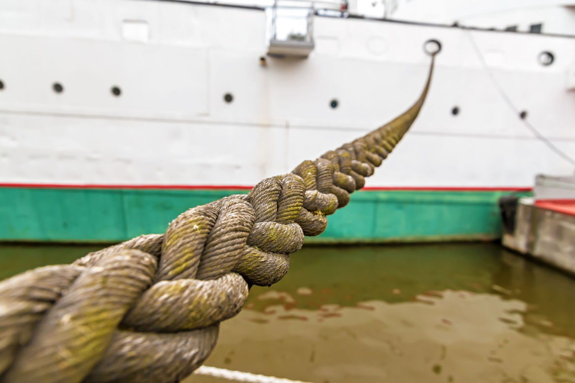 Close-up view to the mooring rope and ship docked in port